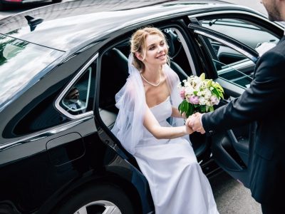 bride arriving in limousine being helped by groom