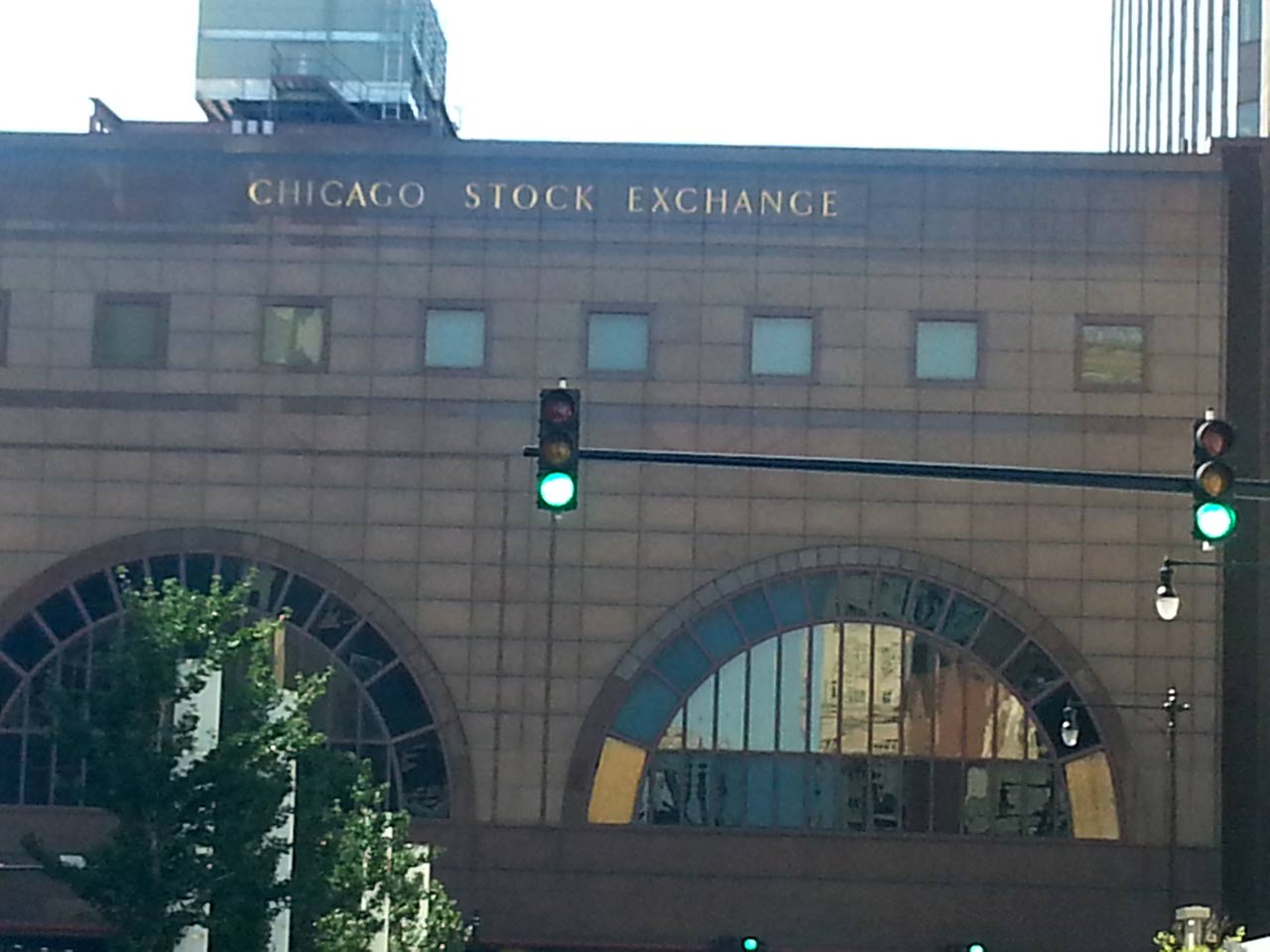 Facade of the Chicago Stock Exchange with arched windows and a street with traffic lights in the foreground