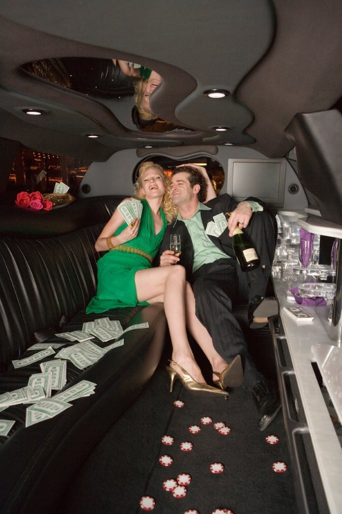 cheerful couple celebrate in limousine with money in Naperville