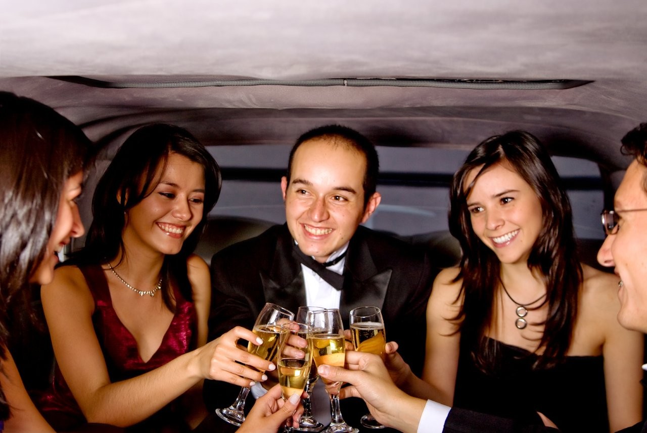 smiling friends toast champagne in a limousine