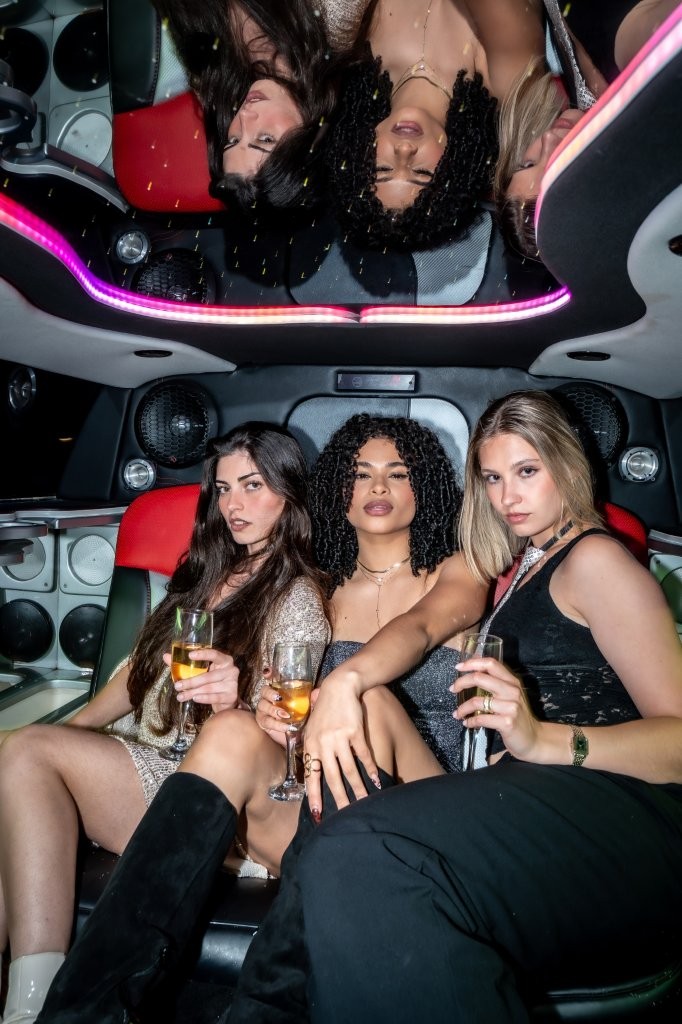 three elegant women celebrating with champagne in a luxury Chicago limo