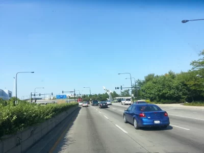 Cars and a shuttle bus on a multilane road approaching an airport terminal