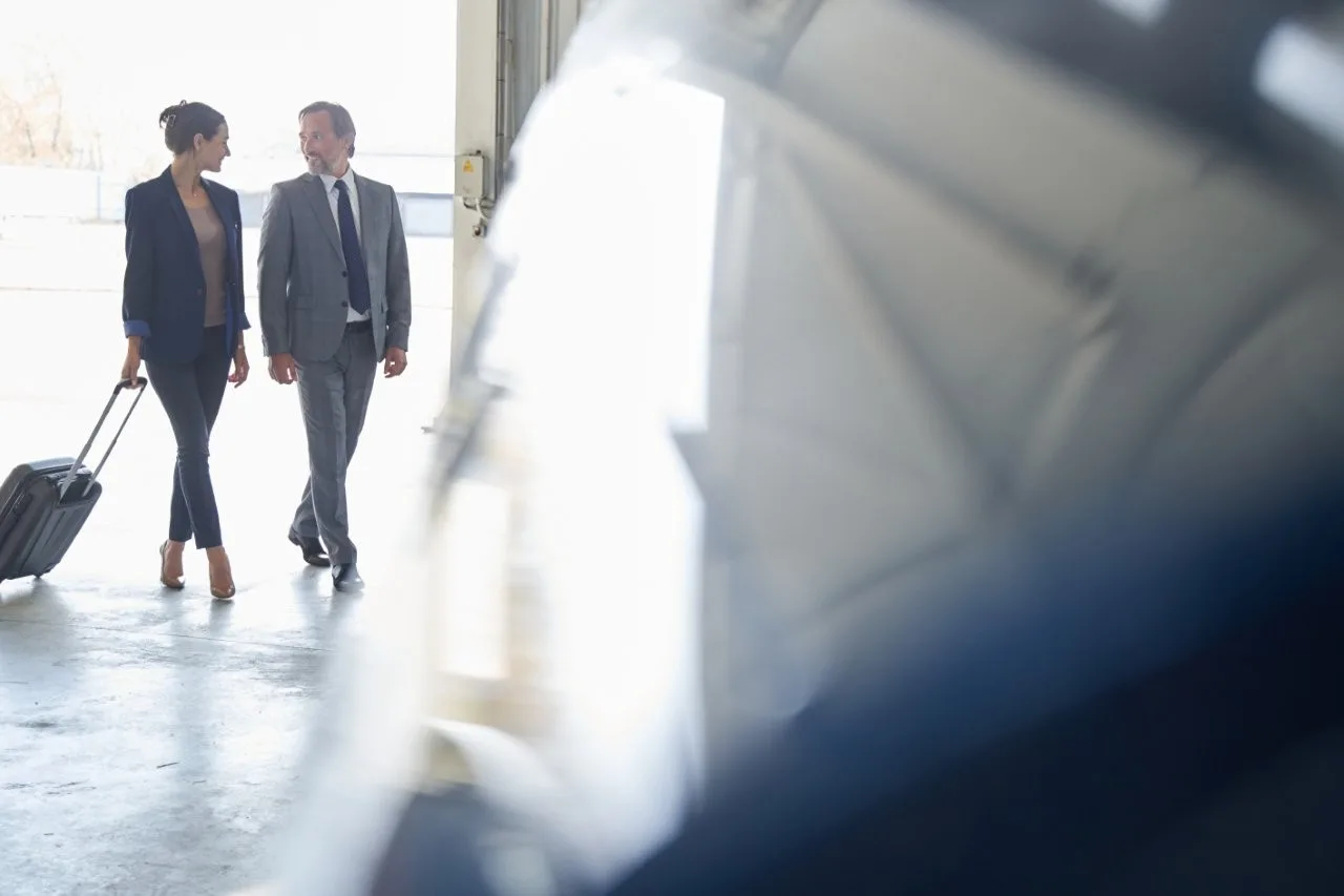 Travelers walking with a suitcase - Go Chicago Limo Two adults in business clothes walking with a rolling suitcase beside a blurred vehicle